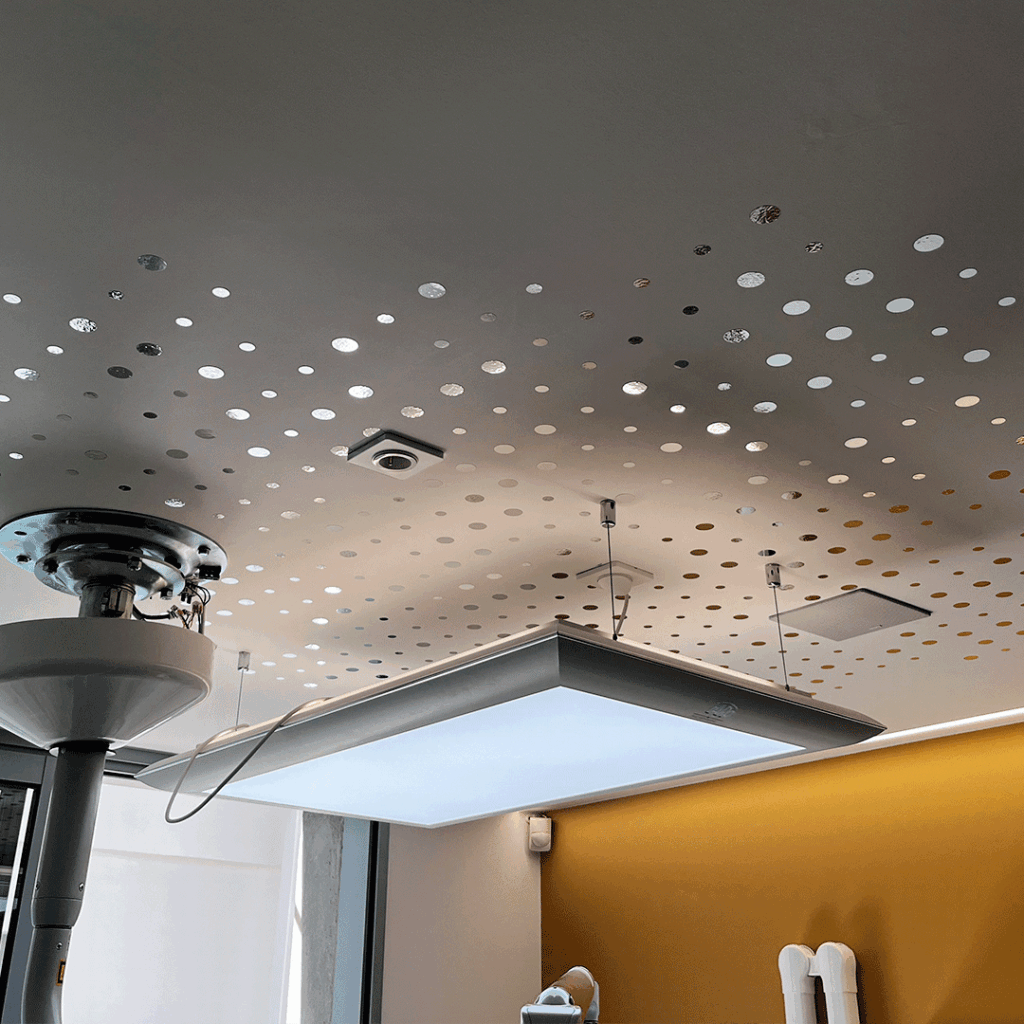 Signalétique lumineuse architecturale au plafond avec grand luminaire suspendu et motifs décoratifs circulaires.