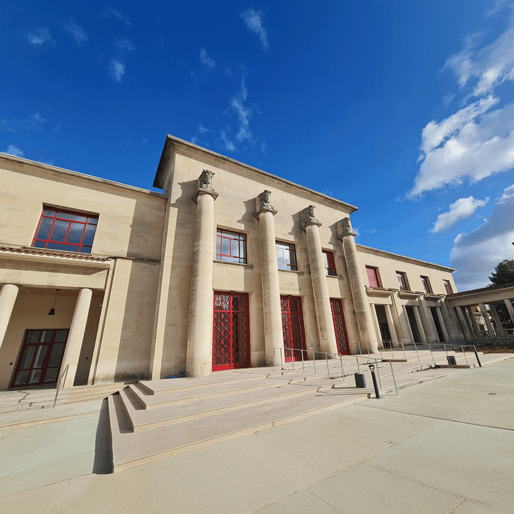 "CITÉ ADMINISTRATIVE" gravé en doré sur la façade d'entrée en pierre, encadré par des colonnes et portes rouges.