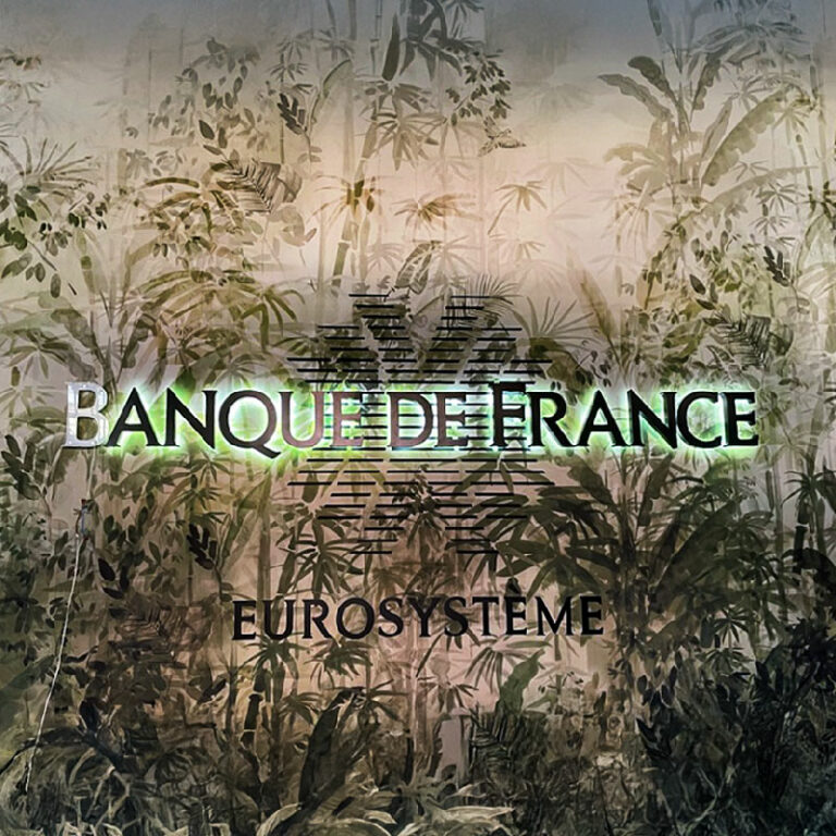 Enseigne murale lumineuse rétroéclairée par LED, lettres boîtiers posées sur un mur décoratif à motif tropical.