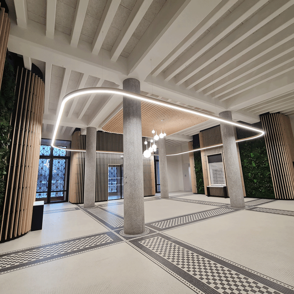 Hall d'accueil de la Cité Administrative de Toulouse avec éclairage LED courbé, colonnes en béton et murs d'accentuation en lattes de bois.