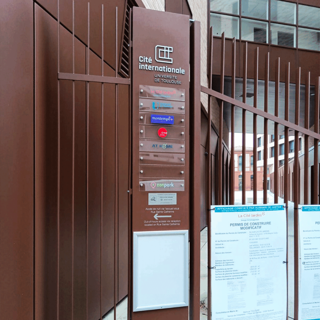 Panneau de signalétique d'information marron fixé sur un portail d'entrée
