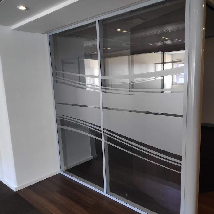 Cloisons vitrées de bureau avec film de vitrophanie dépoli à bandes ondulées pour assurer la confidentialité et le design.